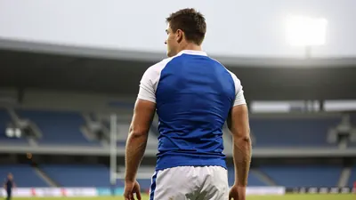 A 25-year-old athletic full-back with a strong build, wearing a blue jersey with white sleeves and a white collar, and...