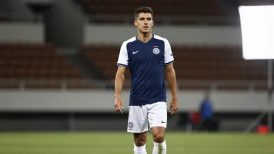 A photorealistic image of a 23-year-old, athletic, and agile midfielder, wearing a dark blue jersey with white sleeves...
