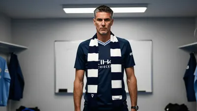 A 45-year-old, tall, and lean Manchester City assistant coach with a stern expression, wearing a dark blue jersey with a...