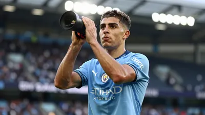 A young, athletic Manchester City midfielder, 22, with short dark hair and determined eyes, wearing the sky blue and navy...