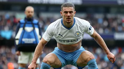 A tight action crop of an anonymous Manchester City player in a white jersey with a blue collar, blue shorts, and blue...