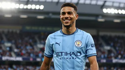 A 30-year-old, athletic Manchester City winger, in sky blue and navy home kit with sharp crest, smiles broadly, eyes...