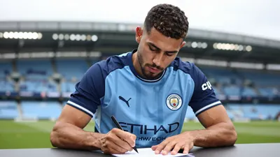 Mid-30s muscular Manchester City midfielder, waist-up, signing transfer paperwork with focused eyes, sky-blue home shirt...