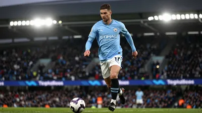 A 30-year-old Manchester City midfielder, wearing a sky blue jersey with a white collar and a pair of black boots, looks...
