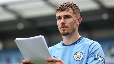 A determined 28-year-old Manchester City sporting director, in a sky blue and navy home kit with the club crest on the...