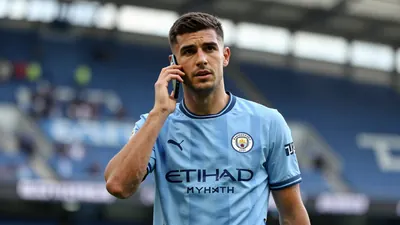 Mid-30s athletic midfielder, dark hair, focused expression, waist-up, wearing Manchester City sky-blue home shirt with...