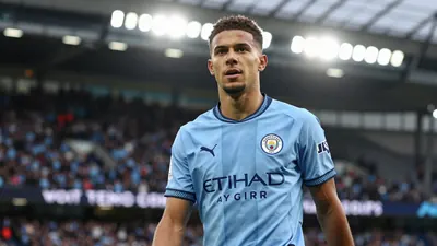 A 30-year-old Manchester City winger, with a lean build and determined expression, wears the sky blue and navy home kit...