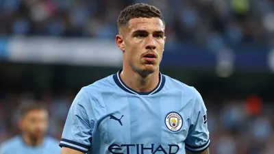 Mid-20s athletic midfielder, tight-cropped waist-up, wearing Manchester City sky-blue shirt with navy sleeves, crisp club...