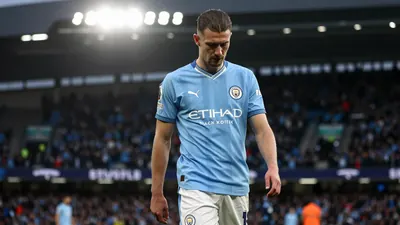 A tight waist-up shot of an anonymous Manchester City player in a sky blue jersey with white sleeves and a white collar...