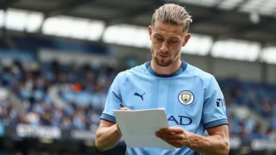 A mid-30s, athletic-built Manchester City midfielder in a sky-blue home jersey with navy sleeves, the club crest...